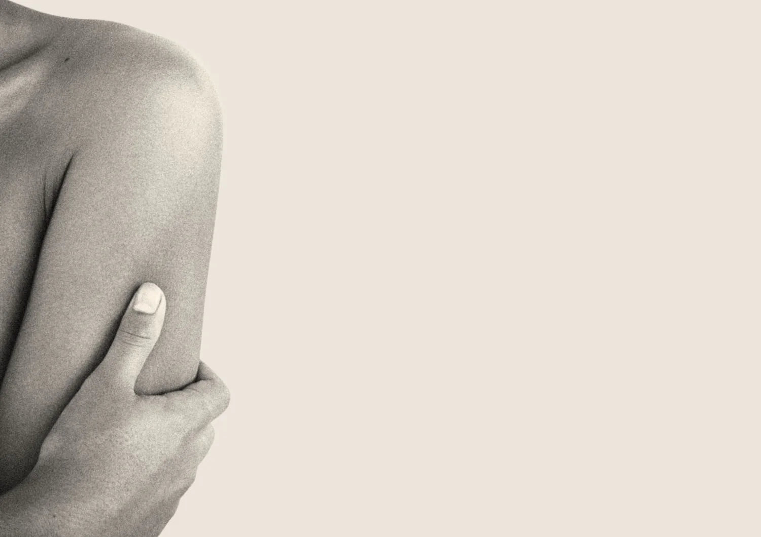 Woman holding their arm with a neutral background