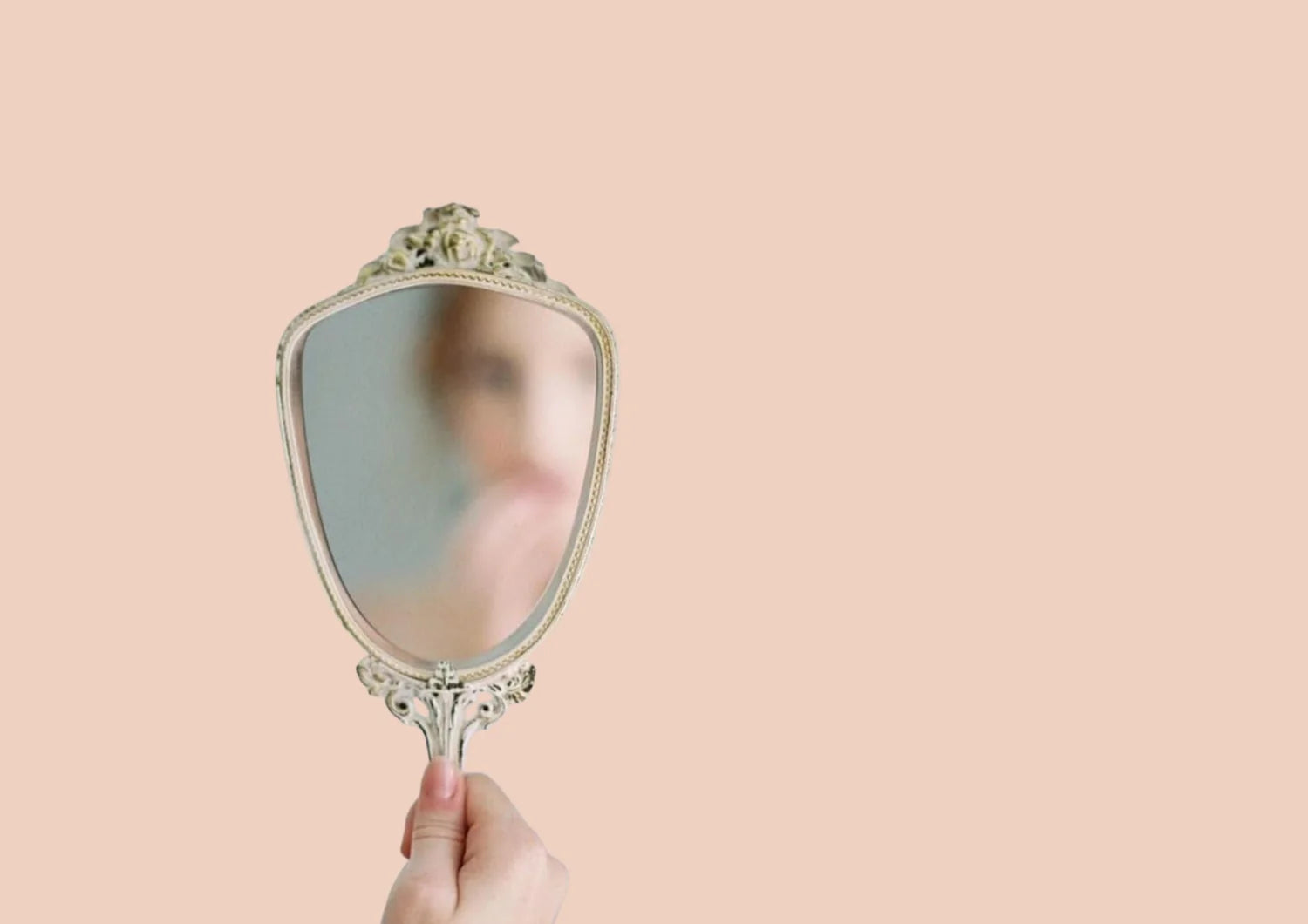 Hand holding a vintage-style hand mirror against a plain background