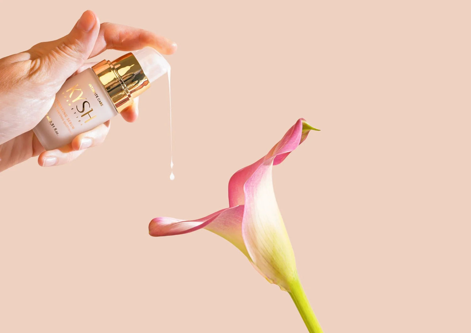 Hand holding a skincare bottle of brand 'KYSH' with droplet over a pink flower on a beige background